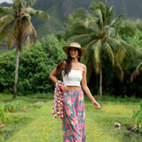 woman with brown hair wearing teal flowy pants with orange and pink foral print