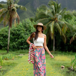woman with brown hair wearing teal flowy pants with orange and pink foral print