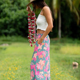 woman with brown hair wearing teal flowy pants with orange and pink foral print
