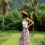 woman with brown hair wearing teal flowy pants with orange and pink foral print