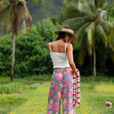 woman with brown hair wearing teal flowy pants with orange and pink foral print