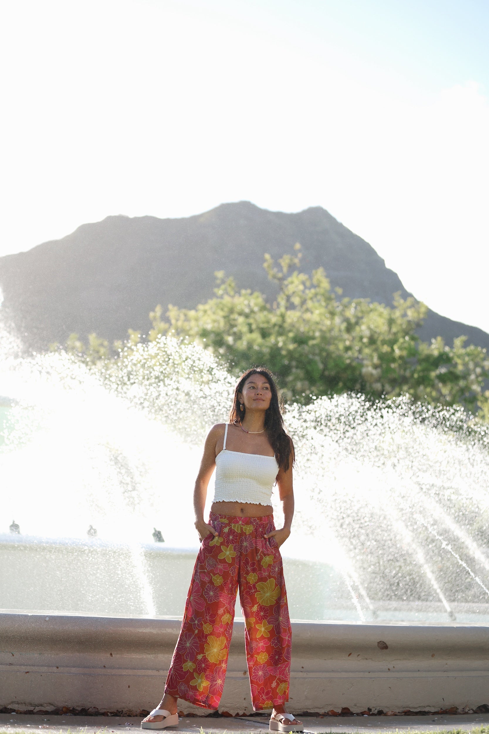 woman wearing terracotta colored pants with large purple and yellow flower print
