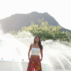 woman wearing terracotta colored pants with large purple and yellow flower print