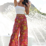woman wearing terracotta colored pants with large purple and yellow flower print
