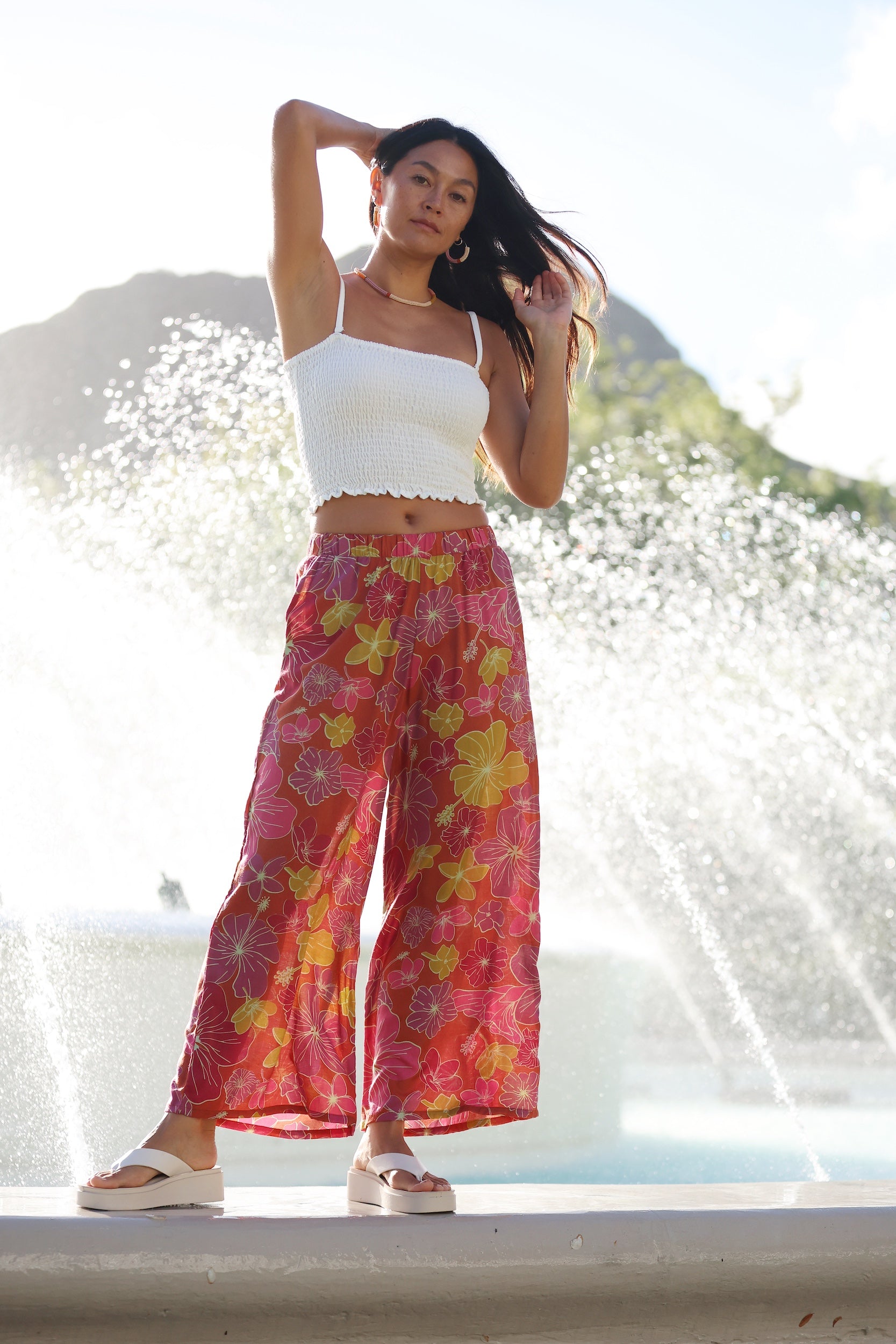 woman wearing terracotta colored pants with large purple and yellow flower print
