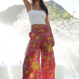 woman wearing terracotta colored pants with large purple and yellow flower print