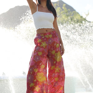 woman wearing terracotta colored pants with large purple and yellow flower print