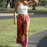 woman wearing terracotta colored pants with large purple and yellow flower print