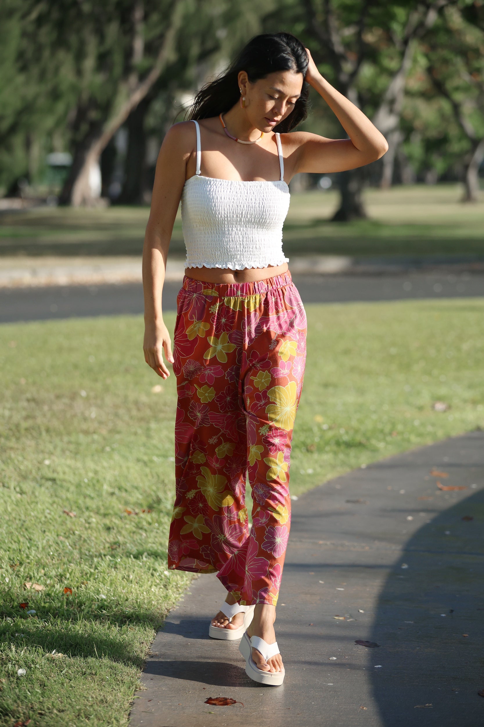 woman wearing terracotta colored pants with large purple and yellow flower print