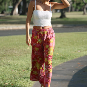 woman wearing terracotta colored pants with large purple and yellow flower print