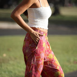 woman wearing terracotta colored pants with large purple and yellow flower print