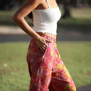 woman wearing terracotta colored pants with large purple and yellow flower print