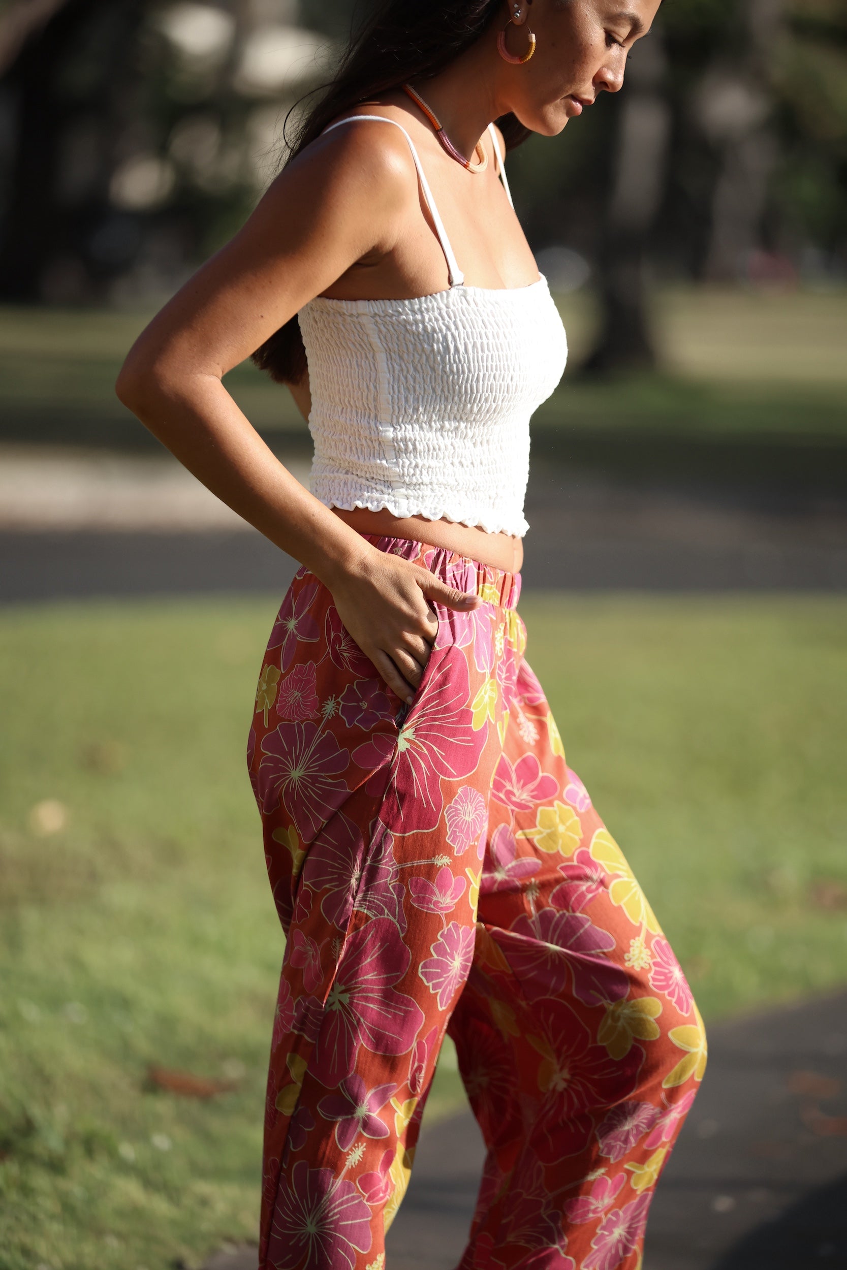 woman wearing terracotta colored pants with large purple and yellow flower print