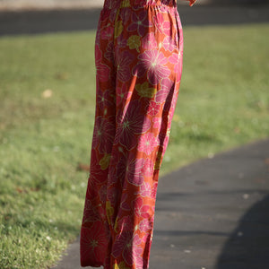 woman wearing terracotta colored pants with large purple and yellow flower print