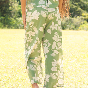 woman wearing green matching top and pant set with native Hawaiian plants 