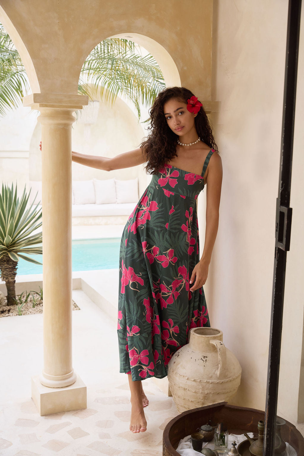 woman with brown hair wearing a dark green thin strap dress with fern and ginger print
