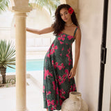 woman with brown hair wearing a dark green thin strap dress with fern and ginger print