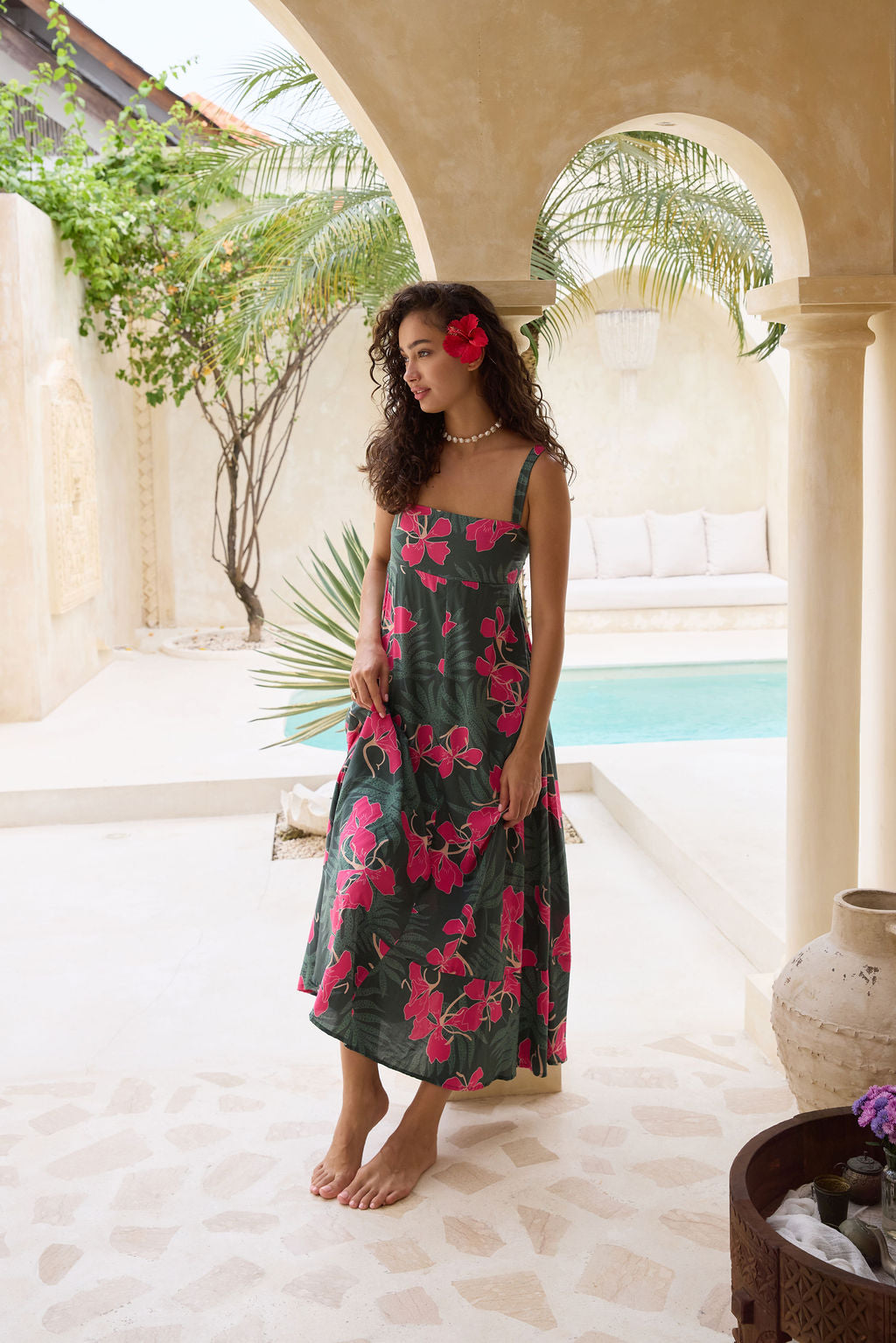 woman with brown hair wearing a dark green thin strap dress with fern and ginger print