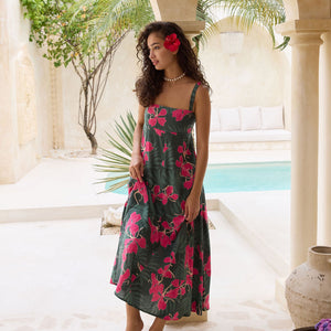 woman with brown hair wearing a dark green thin strap dress with fern and ginger print