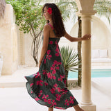 woman with brown hair wearing a dark green thin strap dress with fern and ginger print