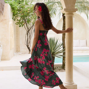 woman with brown hair wearing a dark green thin strap dress with fern and ginger print