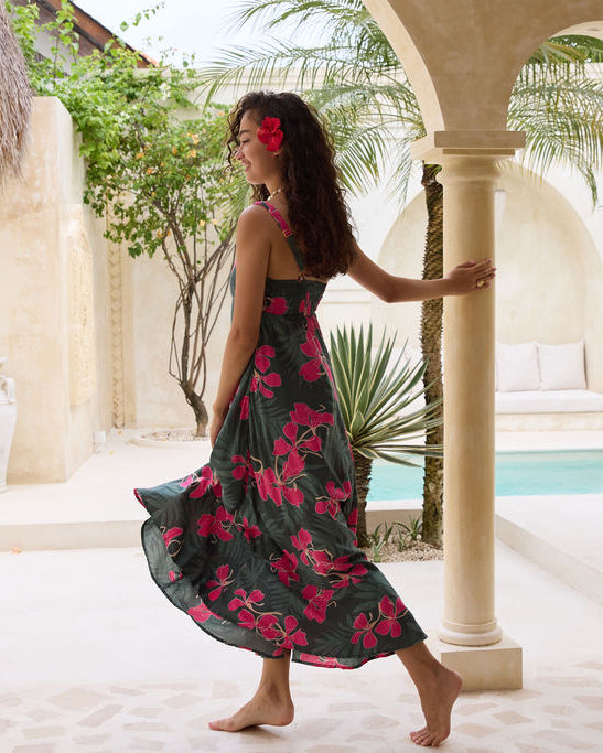 woman with brown hair wearing a dark green thin strap dress with fern and ginger print