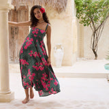 woman with brown hair wearing a dark green thin strap dress with fern and ginger print