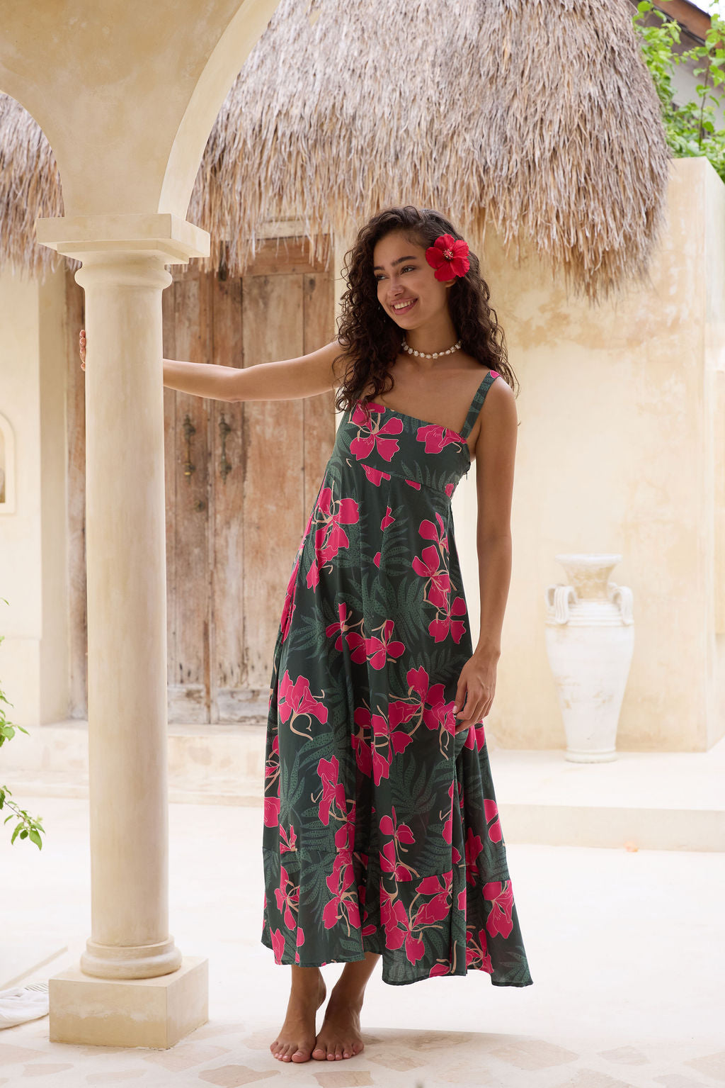 woman with brown hair wearing a dark green thin strap dress with fern and ginger print