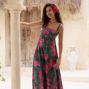 woman with brown hair wearing a dark green thin strap dress with fern and ginger print