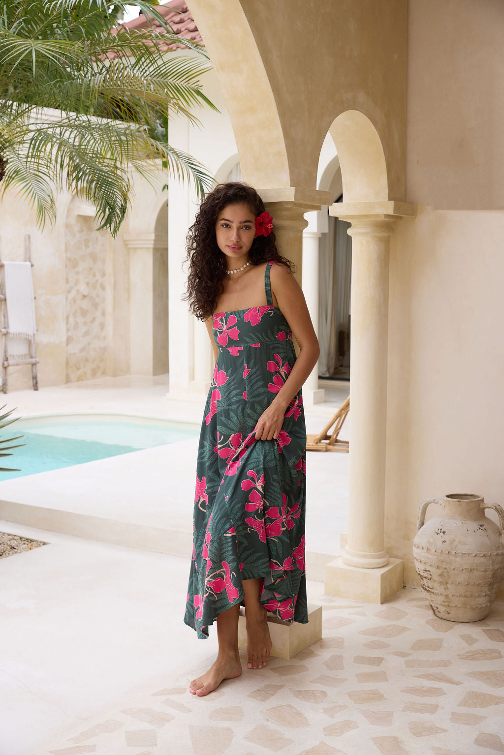 woman with brown hair wearing a dark green thin strap dress with fern and ginger print