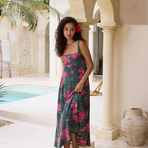 woman with brown hair wearing a dark green thin strap dress with fern and ginger print