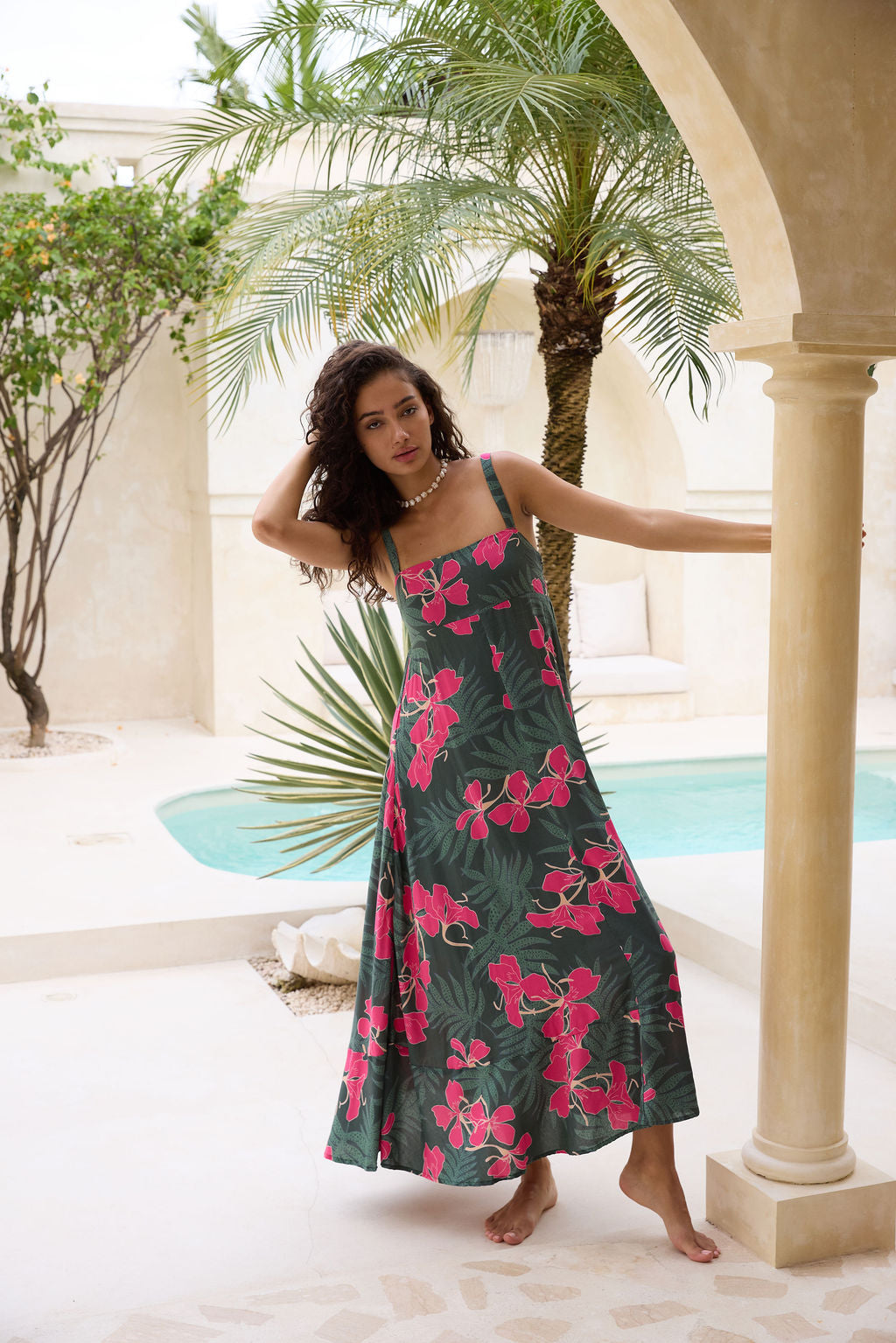 woman with brown hair wearing a dark green thin strap dress with fern and ginger print
