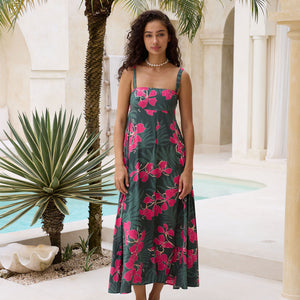 woman with brown hair wearing a dark green thin strap dress with fern and ginger print
