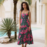 woman with brown hair wearing a dark green thin strap dress with fern and ginger print