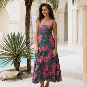 woman with brown hair wearing a dark green thin strap dress with fern and ginger print
