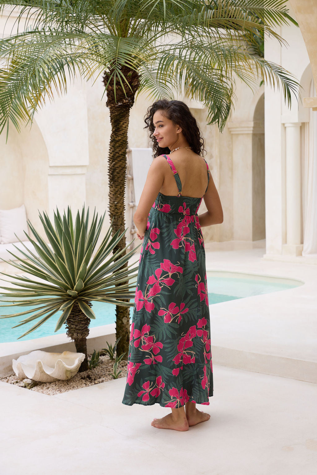 woman with brown hair wearing a dark green thin strap dress with fern and ginger print
