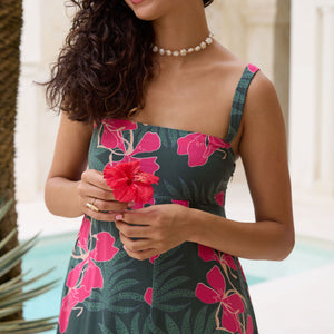 woman with brown hair wearing a dark green thin strap dress with fern and ginger print