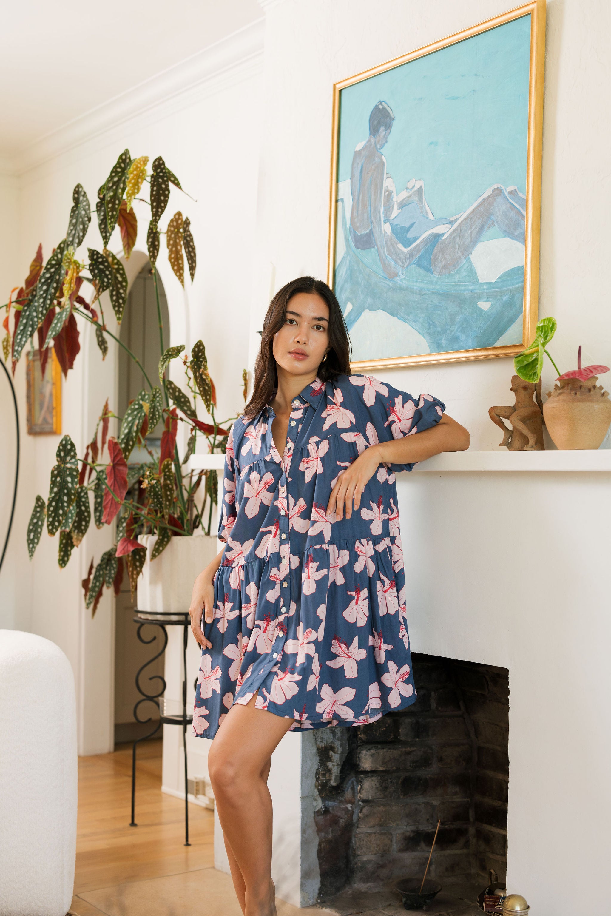 woman with black hair wearing a mini baby doll button up dress in a navy color with pink hibiscus blossoms 