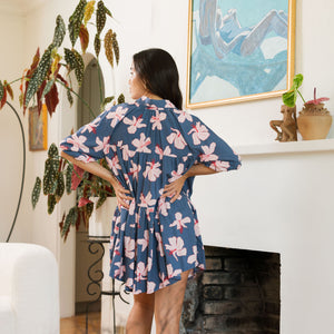 woman with black hair wearing a mini baby doll button up dress in a navy color with pink hibiscus blossoms 
