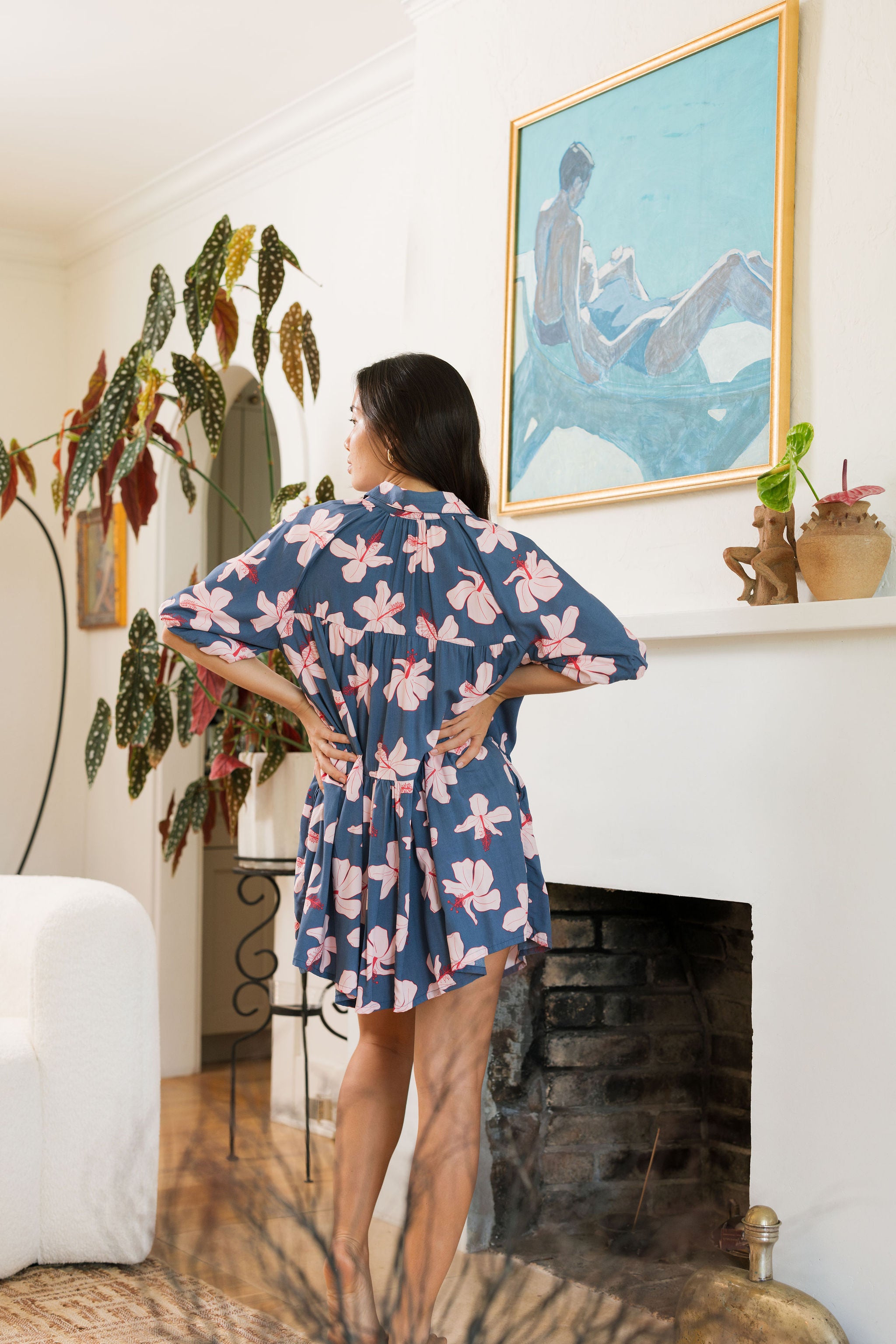 woman with black hair wearing a mini baby doll button up dress in a navy color with pink hibiscus blossoms 
