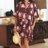 woman wearing brown button up puffy sleeve baby doll dress with protea pattern