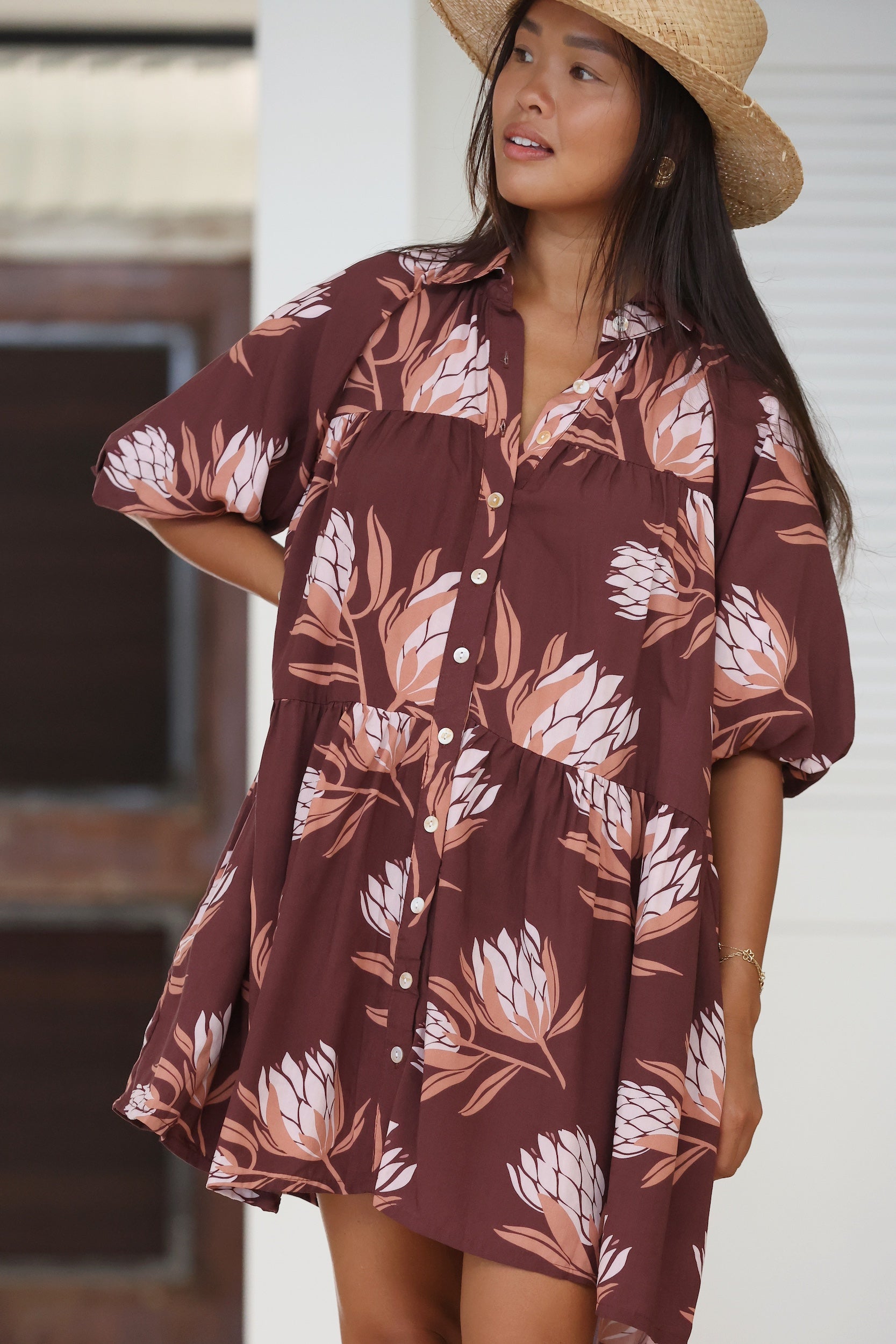 woman wearing brown button up puffy sleeve baby doll dress with protea pattern