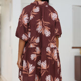 woman wearing brown button up puffy sleeve baby doll dress with protea pattern