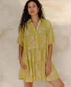 Woman in flowy short sleeve shirt dress with light green and beige floral print.