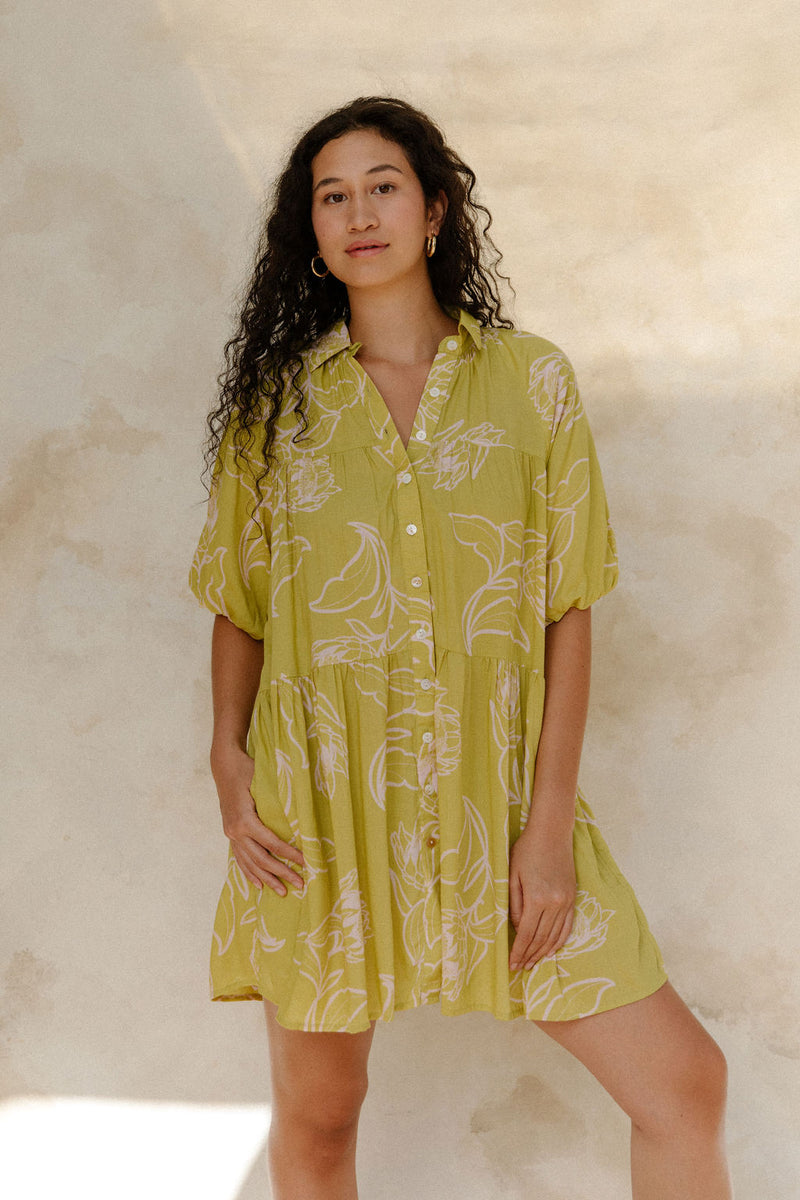 Woman in flowy short sleeve shirt dress with light green and beige floral print.