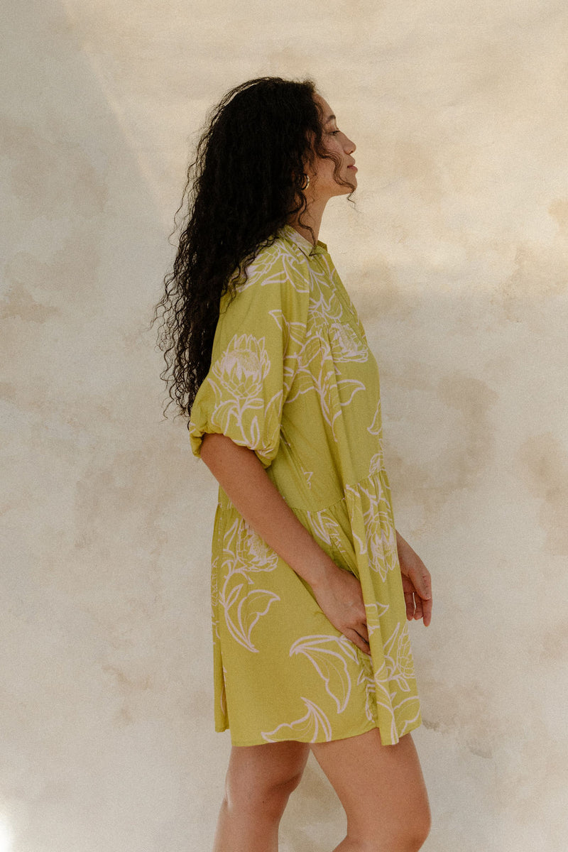 Woman in flowy short sleeve shirt dress with light green and beige floral print.