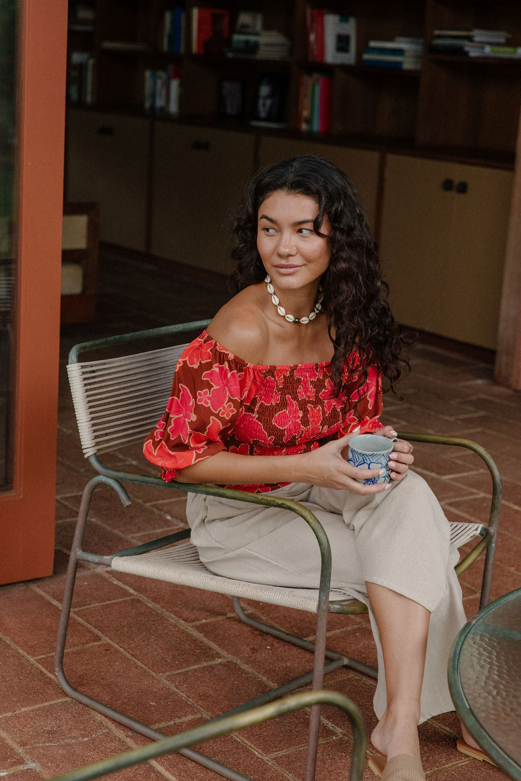 woman wearing versatile smocked top with off the shoulder on the shoulder sleeves in a vibrant retro pink pua print