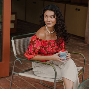 woman wearing versatile smocked top with off the shoulder on the shoulder sleeves in a vibrant retro pink pua print