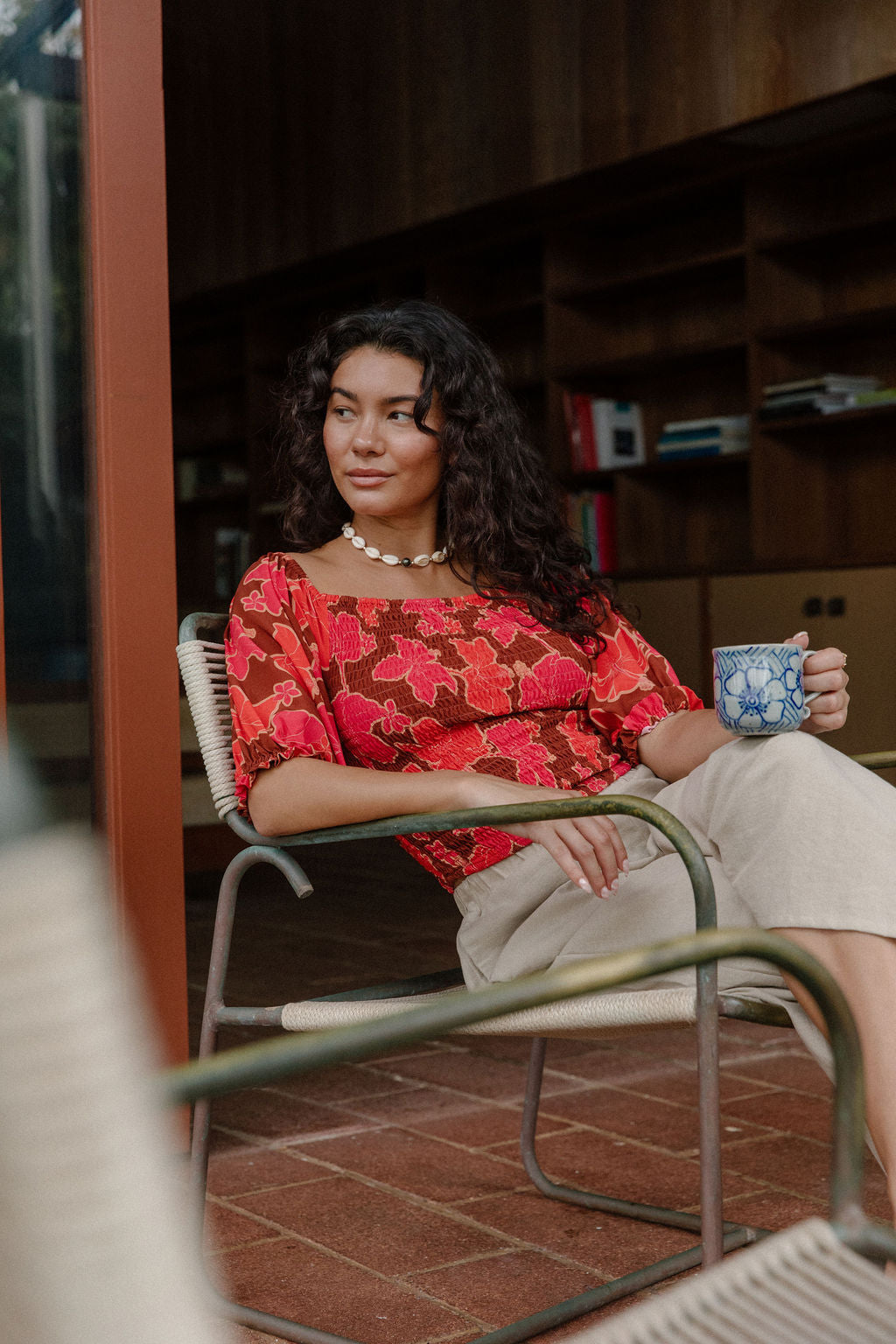 woman wearing versatile smocked top with off the shoulder on the shoulder sleeves in a vibrant retro pink pua print