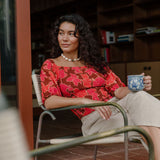 woman wearing versatile smocked top with off the shoulder on the shoulder sleeves in a vibrant retro pink pua print